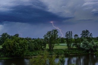 Bright flashes of lightning have illuminated the dark sky over a river, Bogen, Lower Bavaria