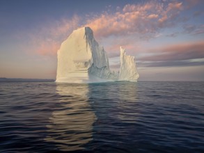 Large glaciers in the bay by the rocky shore in the light of the setting sun