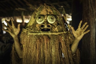 Photo of native man in costume with raised hands in Palembe, Sepik river in Papua New Guinea. In