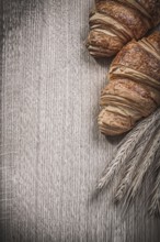 Golden wheat rye ears baked croissants on a wooden board