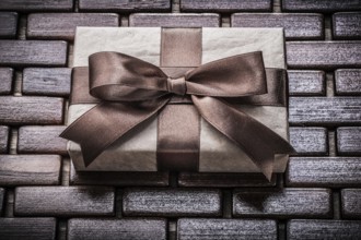 Wrapped giftbox with ribbon on wooden wicker matting holidays concept