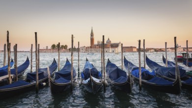 Gondolas moored docked on water in Venice. Gondoliers sailing San Marco basin waterway. San Giorgio