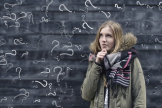 Pretty young female student in class with a problem to solve standing in front of a chalkboard in
