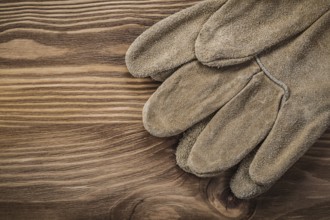 Leather protective gloves on vintage wooden board Construction concept