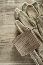 Pair of leather protective gloves Wooden hammer on wooden board '
