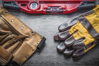 Construction level protective gloves leather tool belt on wood board