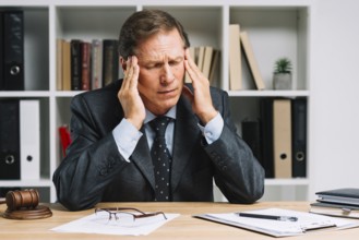 Mature lawyer with headache sitting courtroom
