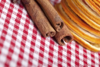 Slices of dried orange and cinnamon sticks on a chequered cloth