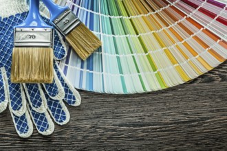 Pair of safety gloves paint brushes color sampler on wooden board
