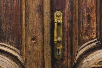 Vintage background. Brass-made old handle with Elements of an carved wooden door decorated with