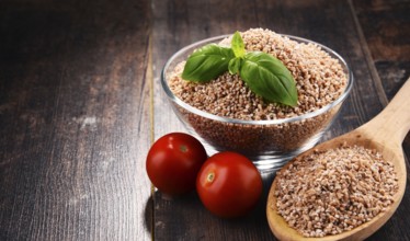 Bowl of uncooked spelt on wooden table