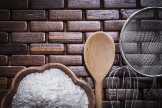 Wood spoon bowl flower sieve and egg-whisk on wooden matting