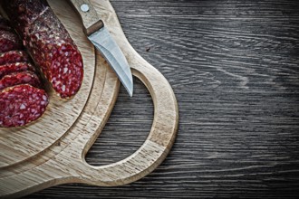 Chopped salami knife on wooden chopping board