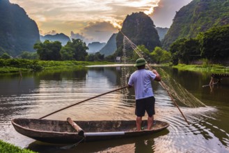 Fisherman on boat in Trang An, a scenic area near Ninh Binh, Vietnam inscribed as a UNESCO World