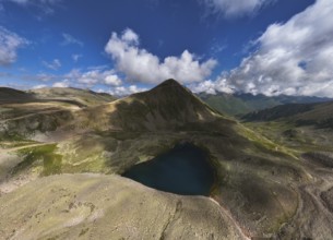 Aerial view of high mountain glacial lake and snow capped mountain peaks. Landscape of an alpine