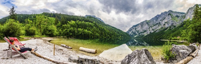 Landscape panorama with woman on sunbed next to the lake Leopoldsteinersee, Styria, Austria. Travel
