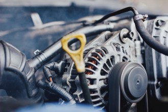 Close view of a car's engine with focus on the alternator and belt, indicating repair work