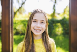 Portrait of modern happy teen girl with braces dressed in yellow clothes in park. Pretty teenage