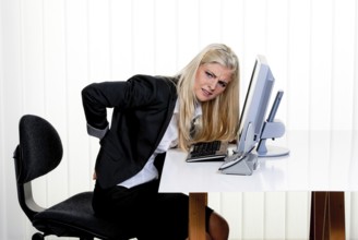 Young woman with back pain in the office