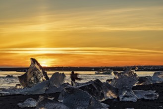 Dancing girl in diamond beach in Vatnajokull National Park at sunset, Iceland, Europe
