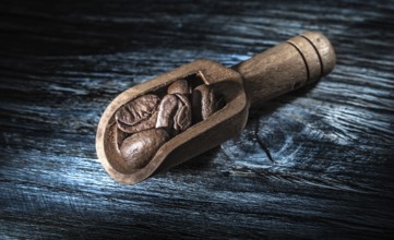 Coffee beans in scoop on wooden board