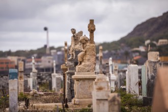 Gravestone in a large cemetery showing a little angelic girl sitting under a cross and engraving