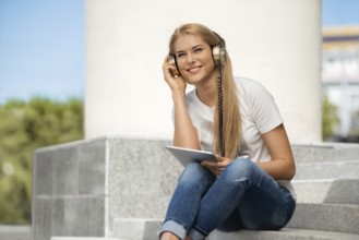Happy young woman listening to music with vintage headphones, surfing the internet on a tablet PC