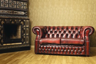 Old Red Genuine Leather Sofa Near The Fireplace