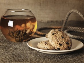 Cookies in front of blossom tea over the burlap background