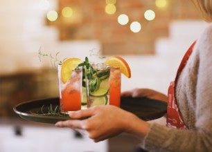 Young pretty woman with red and green cocktails on tray in the bar