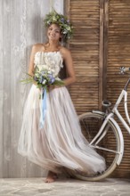 Young beautiful girl in a wedding dress with a bicycle