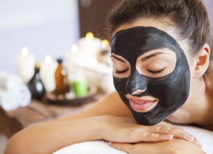Young beautiful woman in a mask for the face of the therapeutic black mud. Spa treatment