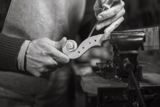 Close-up of a craftsman delicately carving a violin scroll with precision