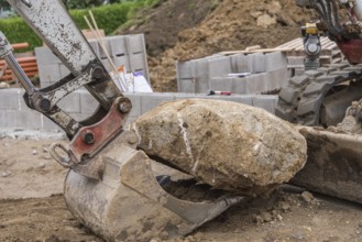 Excavator shovels large stone onto shovel - Construction industry, Construction site