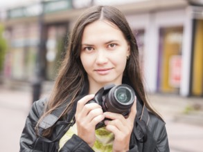 Woman on vacation photographing with dslr camera on city street. Looking at camera. Vacation