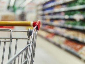 Shopping cart in supermarket. Part of shopping trolley in supermarket aisle. Blurred shelves in