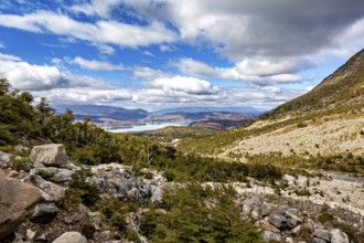 Valley with scattered rocks and views of distant hills and a shimmering blue lake, The landscape of