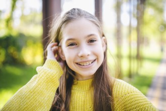 Beautiful and happy teenage girl with braces smiling to camera in yellow clothes in park. Concept