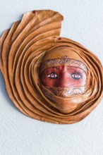 Fashioned from clay mask hanging on a white wall