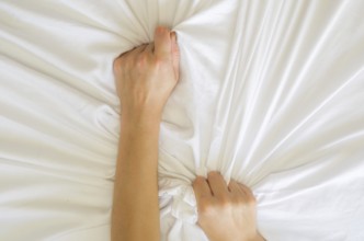 Hand sign orgasm of woman on white bed, Hand of female pulling white sheets in ecstasy, feeling and
