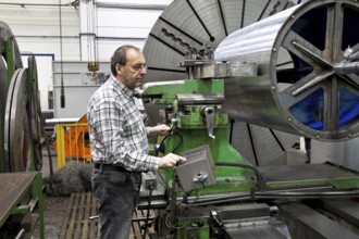 An older worker in the metal industry at a CNC milling machine. Austria