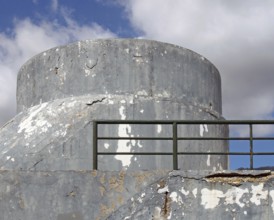 An old crumbling concrete military bunker type structure with rounded windowless surfaces and a
