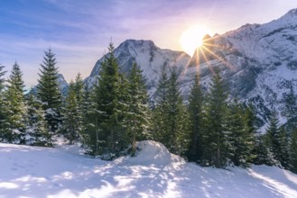 Serene winter landscape with a bright sun shining over the peaks of the Austrian Alps and its