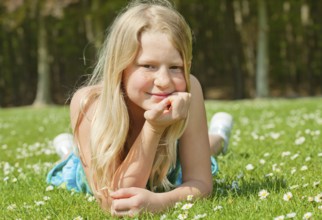 Blond teenager girl lying on the grass in a bright sunny day, Belgium, Europe