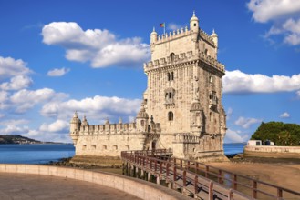 Belem tower and wooden bridge to it, Lisbon, Portugal at blue summer day sky with clouds. Medieval