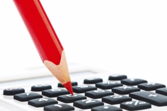 A red pencil and a calculator. Symbolic image Rationalise and save Austria