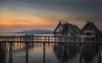 Weathered wooden cabins built on wooden pillars over the Bodensee lake water, at colorful sunset,
