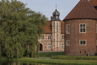 Historic ensemble of buildings with round tower and moat, surrounded by greenery, Raesfeld,