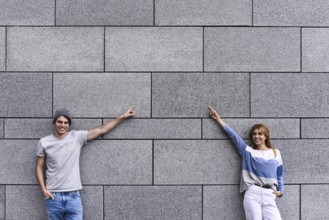 Cheerful couple at the street, show a big sale, or nice offer. Advertise concept. People, travel