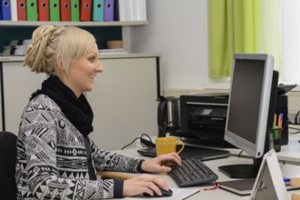 Friendly executive secretary works at the computer workstation